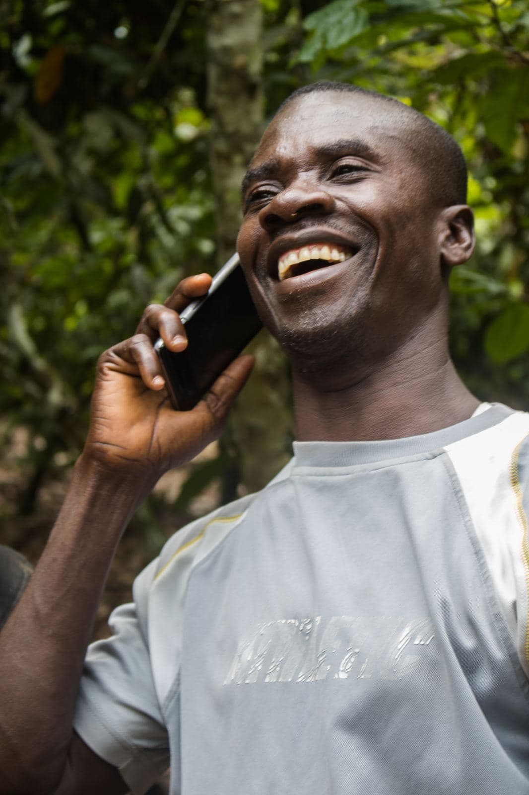 A cocoa farmer laughing while on a phone call in Ghana